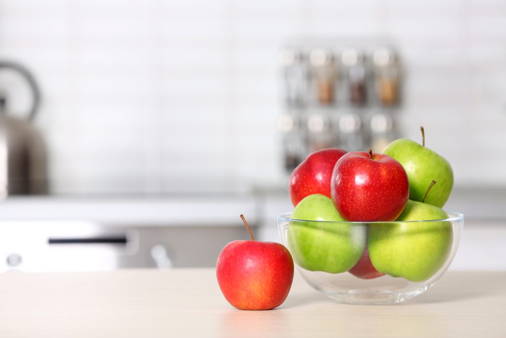 A bowl of red and green apples sitting on a kitchen counter.