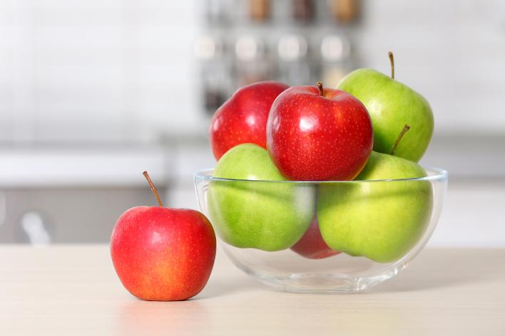 Bowl of red and green apples on counter.